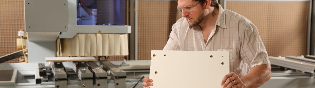 Paladin Industries team member holding a piece of laminate coated wood.